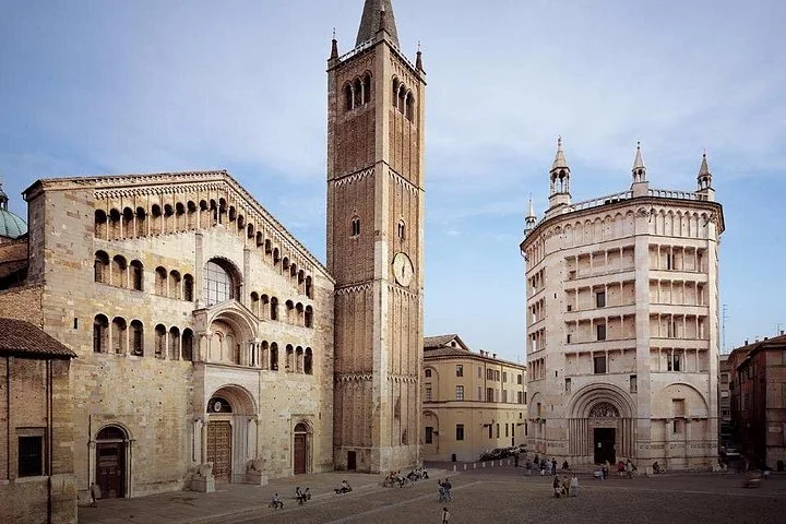 Parma's Romanesque cathedral and its brick bell tower beside the pink marble octagonal baptistery, on a wide square